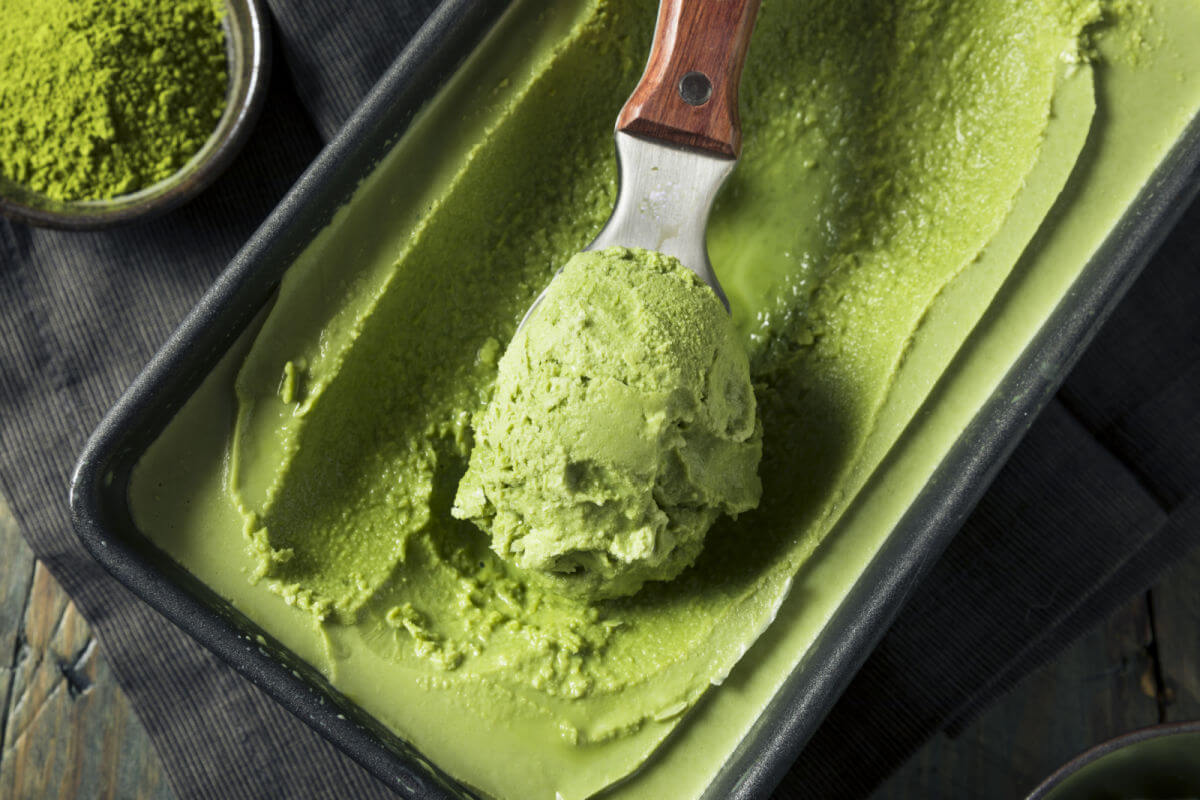 Loaf pan with homemade creamy matcha lychee ice cream being scooped out.
