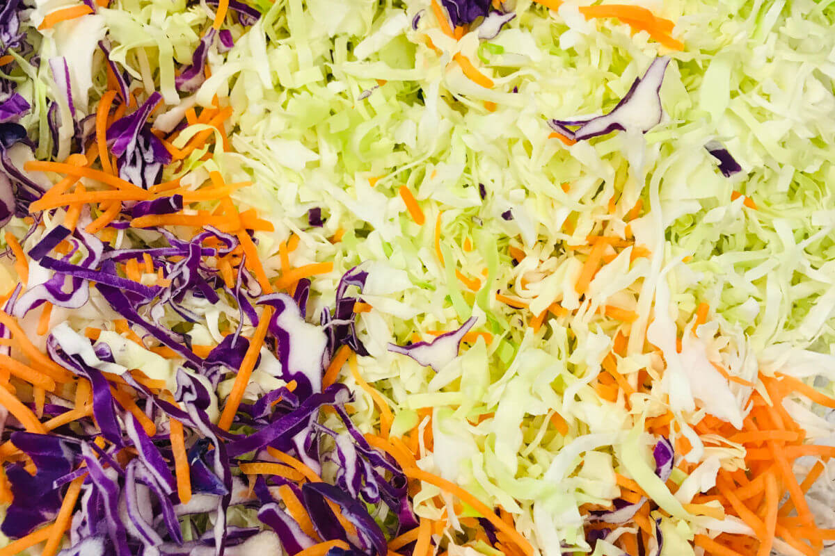Bowl of shredded cabbage, carrots, pear, and cilantro to make Crunchy Asian Slaw.