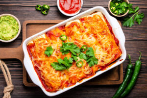 Baking dish of Truckstop Enchiladas, which are spicy ground beef wrapped in tortillas and baked in a zesty tomato sauce and cheese.