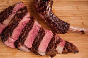 Sliced, rare, tomahawk steak on cutting board