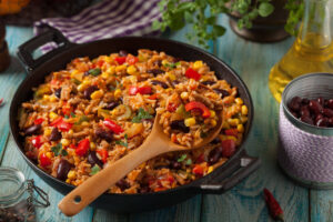 Cast iron skillet of Spicy Mexican Rice Pilaf - spicy rice, black beans, corn, and peppers in a savory chili sauce.