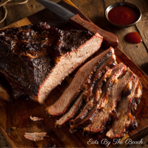 Slices of juicy, oven roasted beef brisket on a wooden board