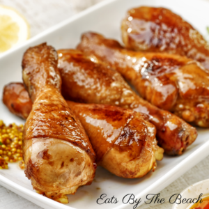 Spicy, Asian inspired glazed chicken drumsticks on a white plate.