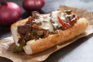 Philly cheesesteak hoagie on brown paper.