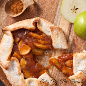 A serving board with a rustic apple galette of apples, honey, and apple butter