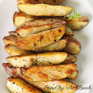 A plate of crispy oven baked potato wedges seasoned with olive oil, salt, onion and garlic powders, and rosemary. An easy and healthy side dish.