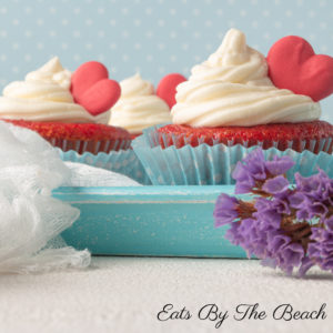 Plate of Red Velvet cupcakes with Cream Cheese Frosting and decorated with a red heart cookie.