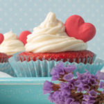 Plate of Red Velvet cupcakes with Cream Cheese Frosting and decorated with a red heart cookie.