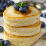 A plate of Japanese Pancakes - which are light, tender, and airy, souffle-like pancakes and garnished with blueberries and a sprig of mint.