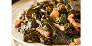 Bowl of Southern Style Slow cooked side dish of collard greens braised with onion, garlic, spices, and a ham hock to a tender, silky green and the most flavorful pot liquor.