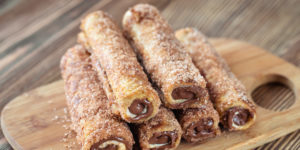 Plate of Stuffed French Toast Roll Ups - stuffed with sweetened cream cheese and nutella, then cooked and rolled in cinnamon sugar. Served with maple syrup, this is a great grab and go breakfast.
