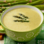 Bowl of smooth and creamy Cream Of Asparagus Soup, garnished with the tops of the asparagus.