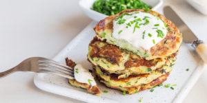 Plate of savory zucchini pancakes garnished with a dollop of sour cream and a sprinkle of chopped chives