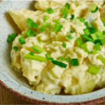 Bowl of creamy, tangy Southern Potato Salad garnished with sliced scallions.
