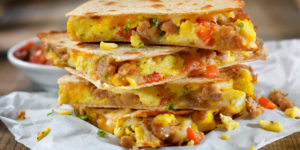 A plate of Easy Breakfast Quesadillas with scrambled egg, sausage, scallions, red bell peppers, and cheddar cheese.
