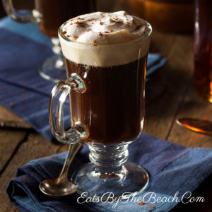 Amug of steaming Irish Coffee garnished with whipped cream and a sprinkle of grated chocolate