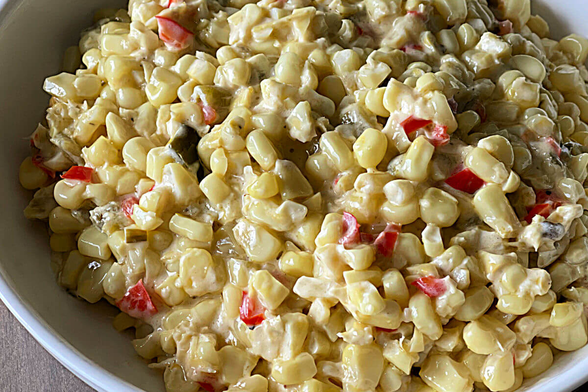 Bowl of green chile creamed corn with fresh corn kernels. jalapenos, canned green chiles in a creamy sauce.