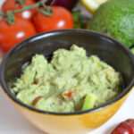 Bowl of The Best Guacamole with onion, lime, jalapenos, and tomatoes. Perfect for CInco De Mayo.