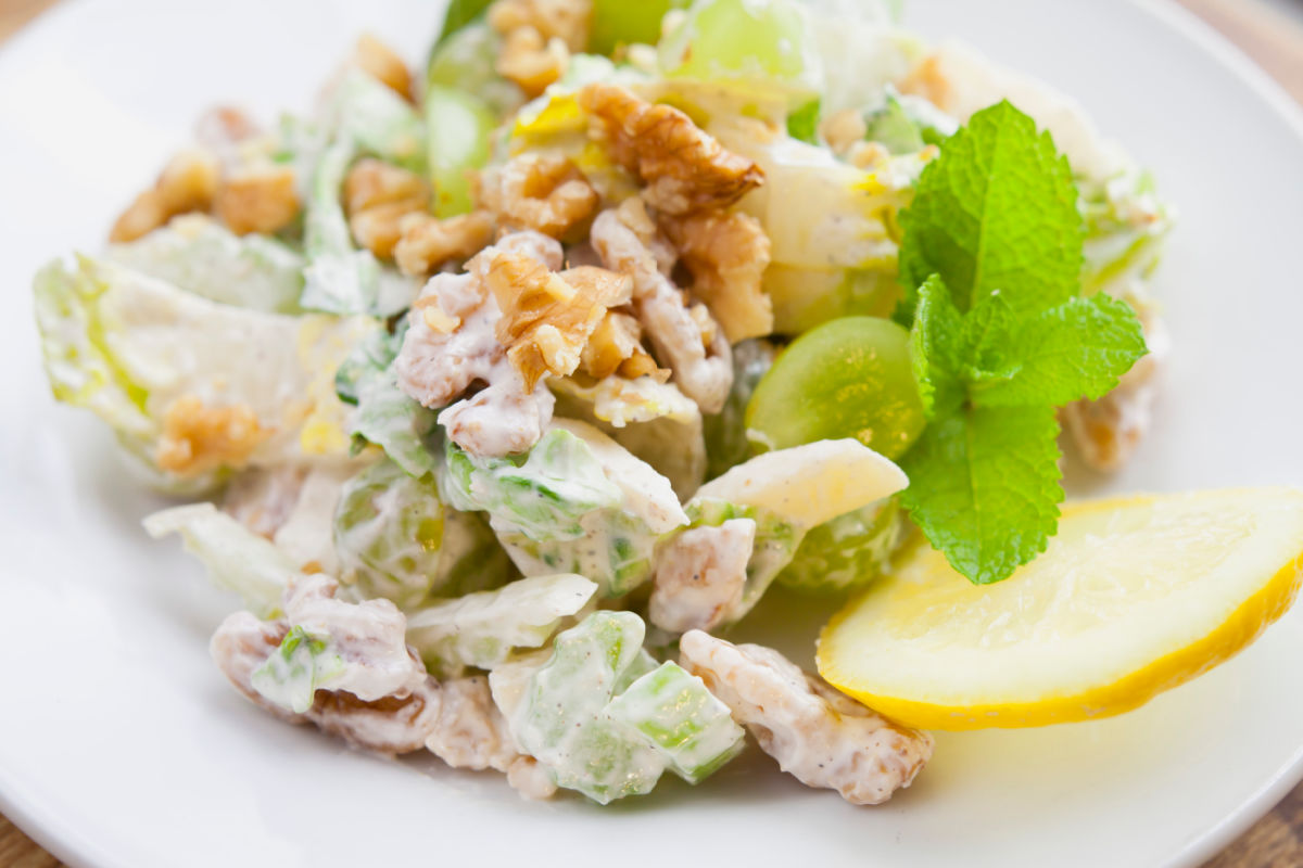 Plate of Classic Waldorf Salad-chopped apples, celery, walnuts, romaine lettuce, and grapes in a creamy yogurt dressing