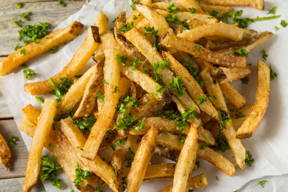 Parmesan Truffle Fries on white paper, garnished with fresh parsley.