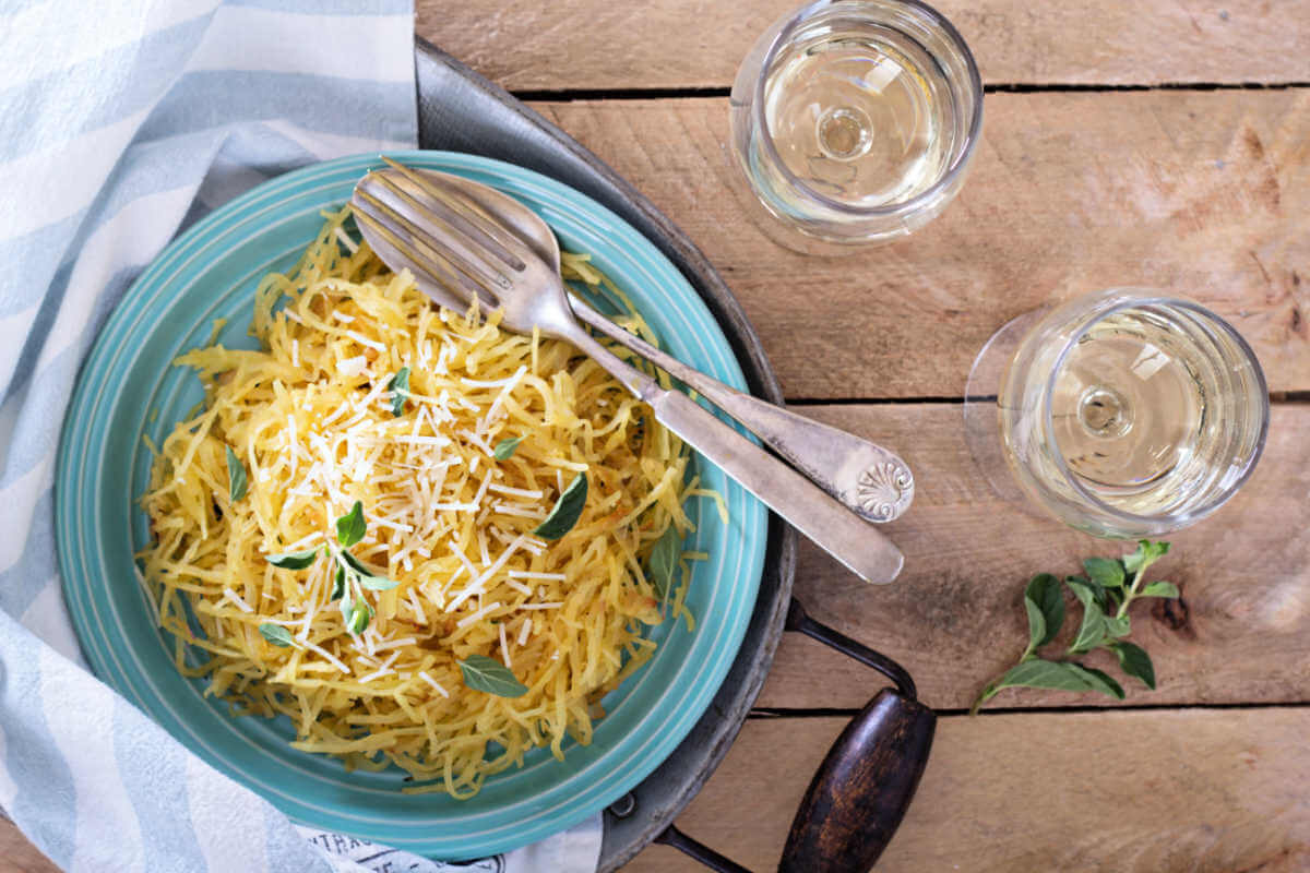 Blue bowl with a serving of brown butter garlic parmesan spaghetti squash and garnished with fresh sage leaves.