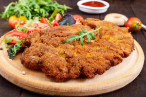 Wooden plate with a pan-fried German Chicken Schnitzel