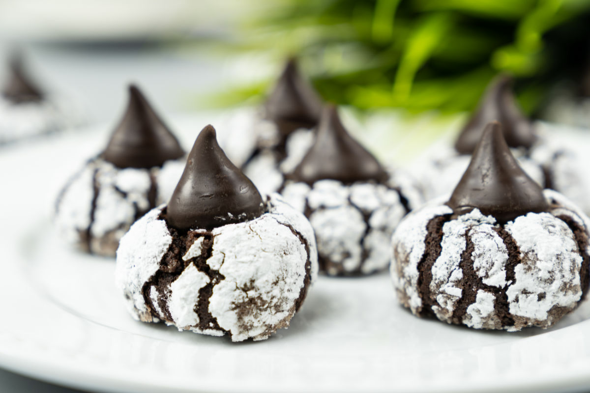 Closeup of chocolate crinkle kiss cookies - chocolate cookies, rolled in powdered sugar and topped with a chocolate kiss candy.
