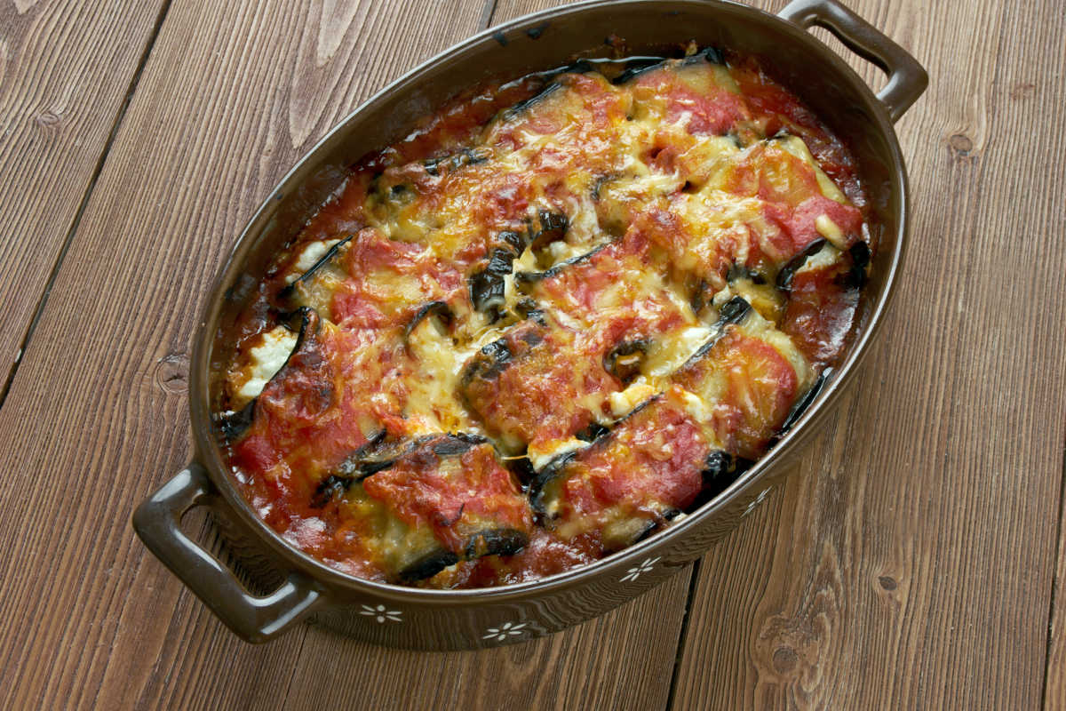 Casserole dish of Involtini Di Melanzane - eggplant rolled around ricotta cheese filling and baked in a homemade marinara sauce.  A perfect meatless Monday dish.