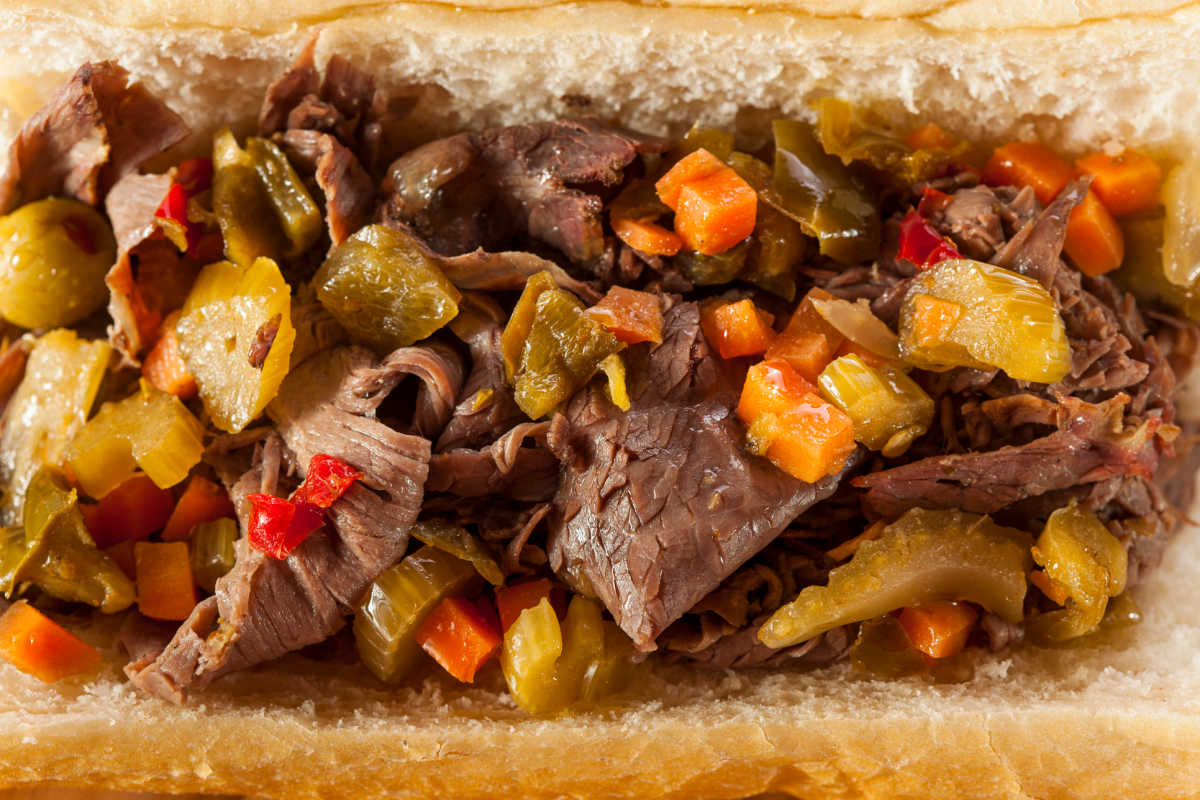 Closeup of an Authentic Italian Beef Sandwich topped with hot Giardiniera.