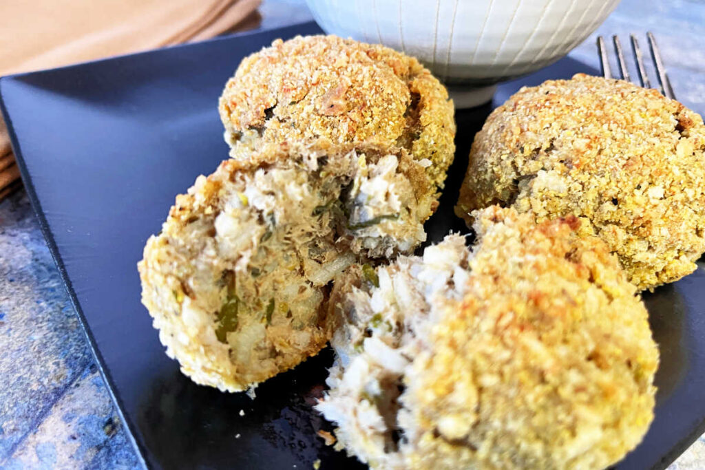 Close up view of brown plate with baked boudin balls with remoulade sauce.