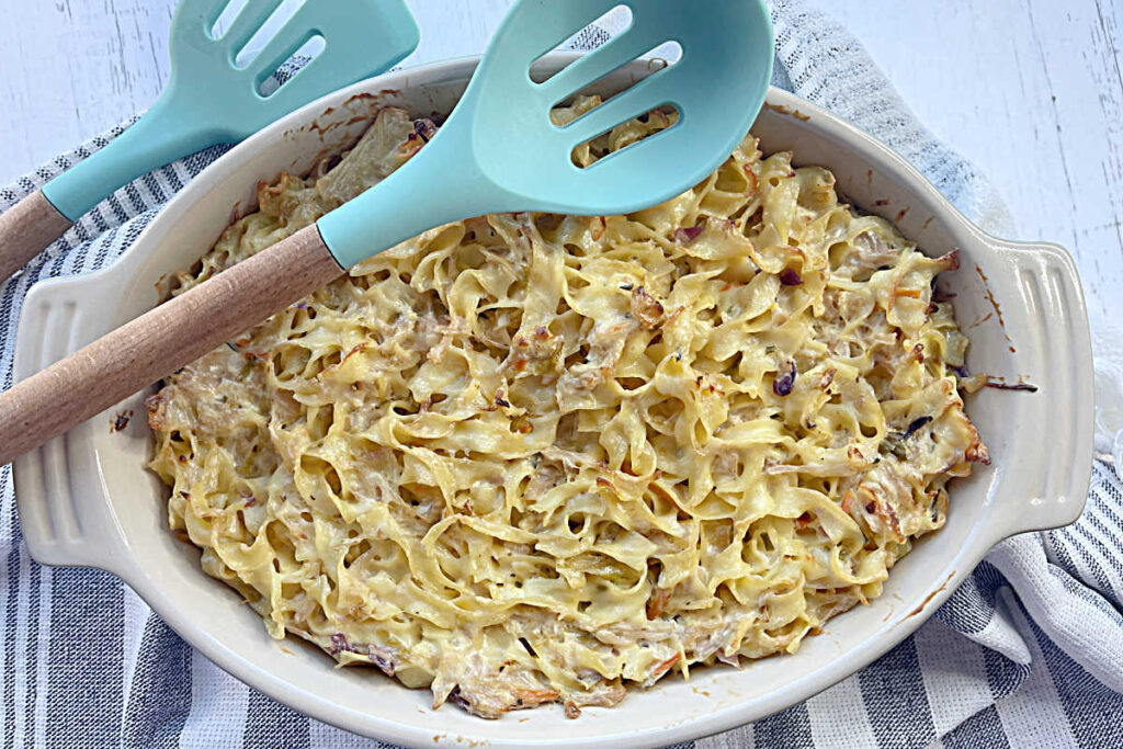 Close up, top view, of a casserole dish with caramelized onion and cabbage kugel with a turquoise serving spoon on the side of the casserole dish.