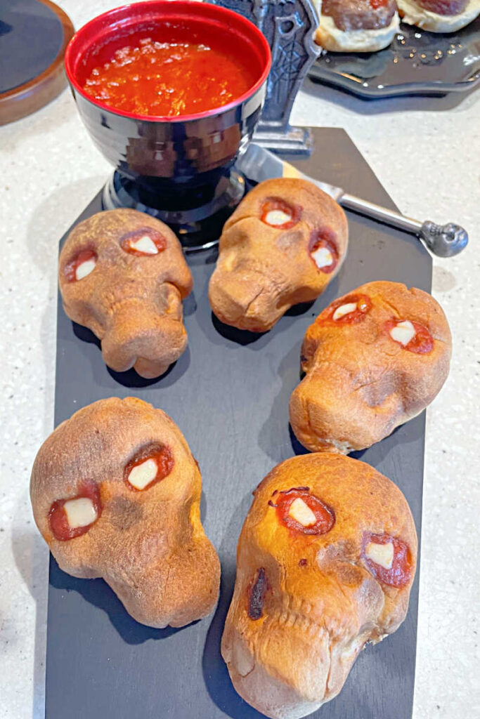 Spooky tray with individual Skull Calzones - pizza dough filled with sauce, cheese, ricotta, and pepperoni and baked in a skull shaped muffin tin.