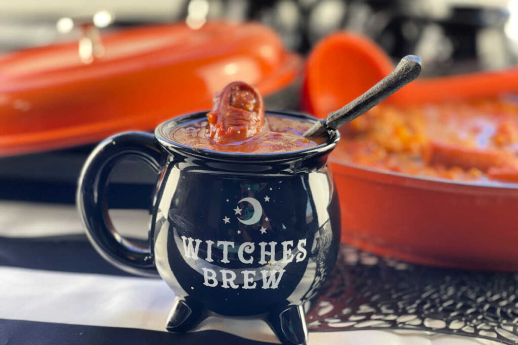 Black Witches Brew Cauldron soup bowl with Zombie Finger Stew - baked beans with a hot dog shaped like a finger and a 'bone' spoon.