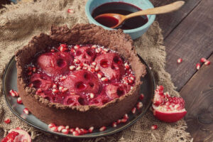 Whole Grim Reaper Pear And pomegrnate pie with pear halves carved to look like skulls and glazed with a pomegranate jelly in a rough edge chocolate shortbread crust. The pie is garnished with pomegranate seeds.