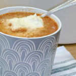 A serving of Lasagna Soup in a gray mug and garnished with a dollop of ricotta cheese and parmesan cheese. Comfort food.