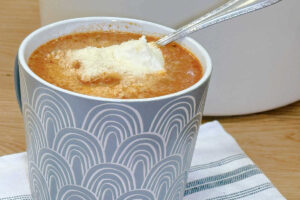 A serving of Lasagna Soup in a gray mug and garnished with a dollop of ricotta cheese and parmesan cheese. Comfort food.