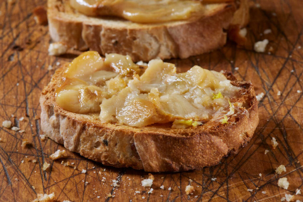Roasted garlic spread on a toasted sourdough bread slice.