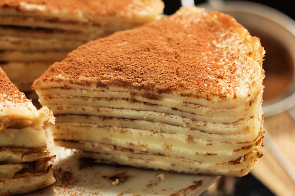 Slice of Stacked Tiramisu Crepe Cake. A cake made of layers of crepes and mascarpone cheese. Side view.